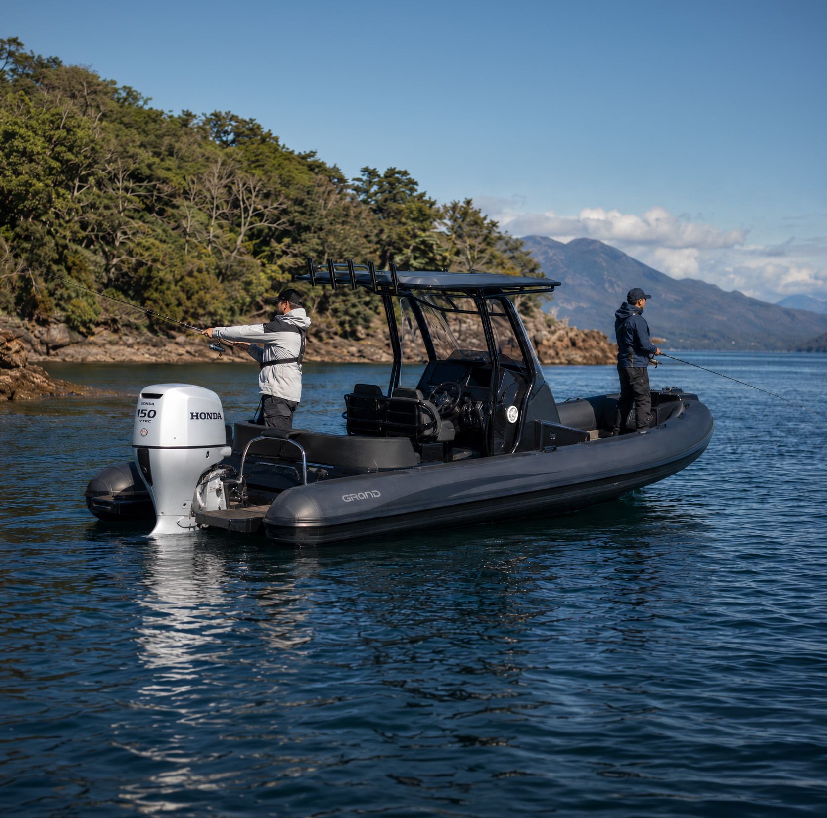 Lancha semirrígida con un motor fuera de borda Honda BF150 blanco en la popa y dos personas pescando, en un lago rodeado de bosque y montañas.